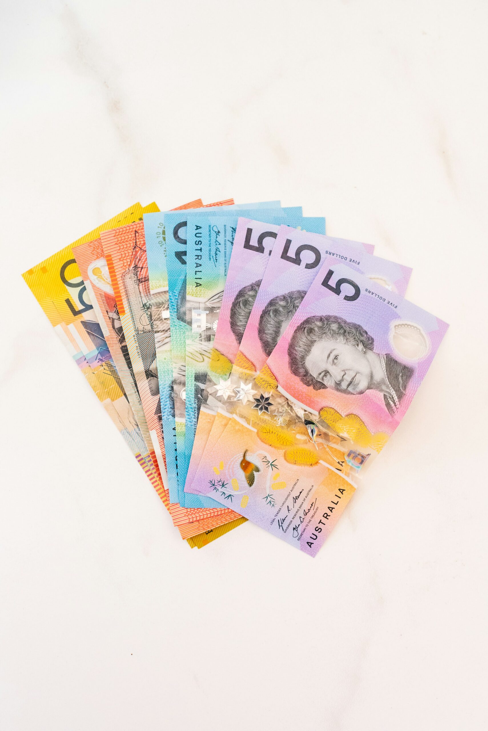 A fan of colourful Australian dollar banknotes on a white surface
