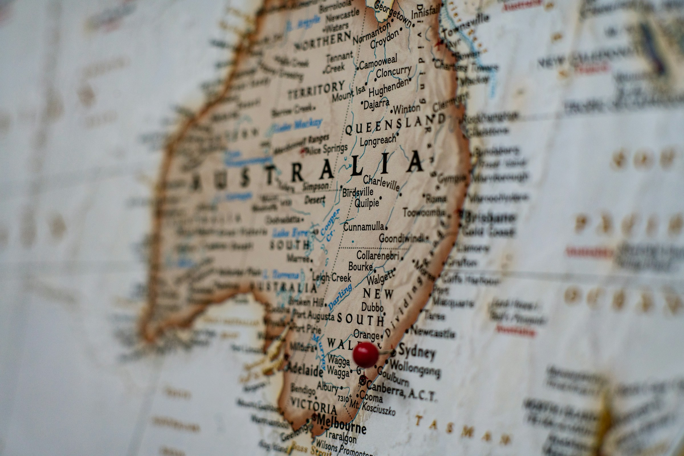A paper map of Australia with a red pin in it