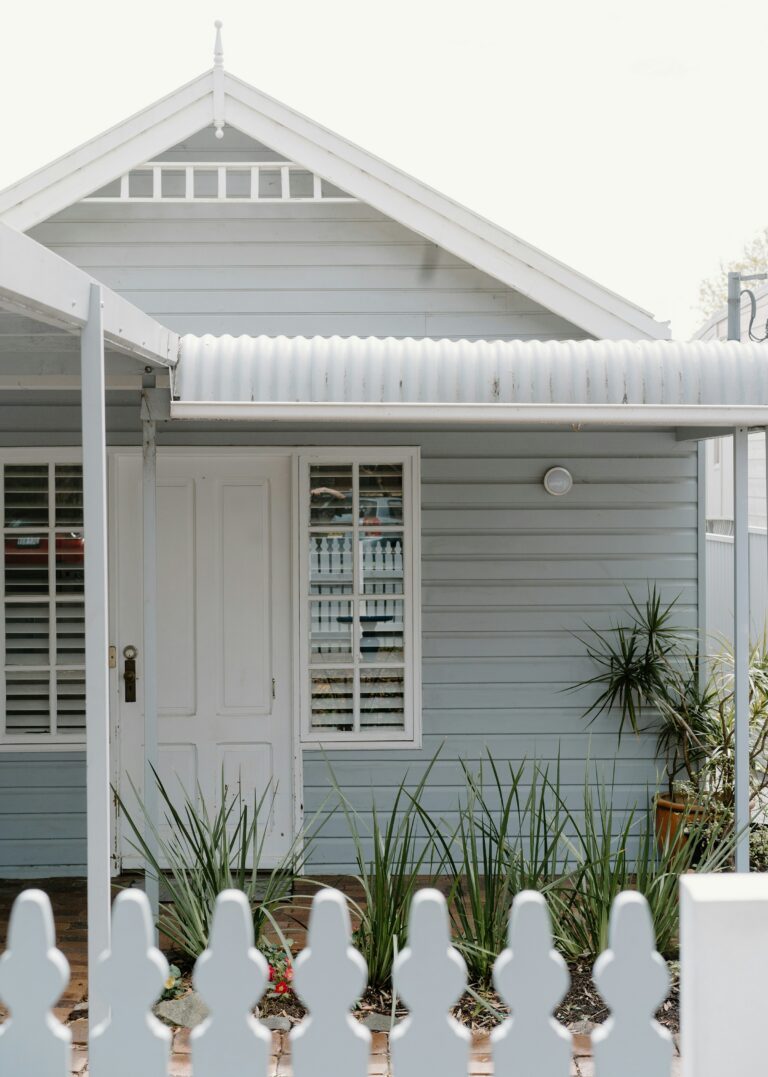 A white weatherboard house behind a picket fence