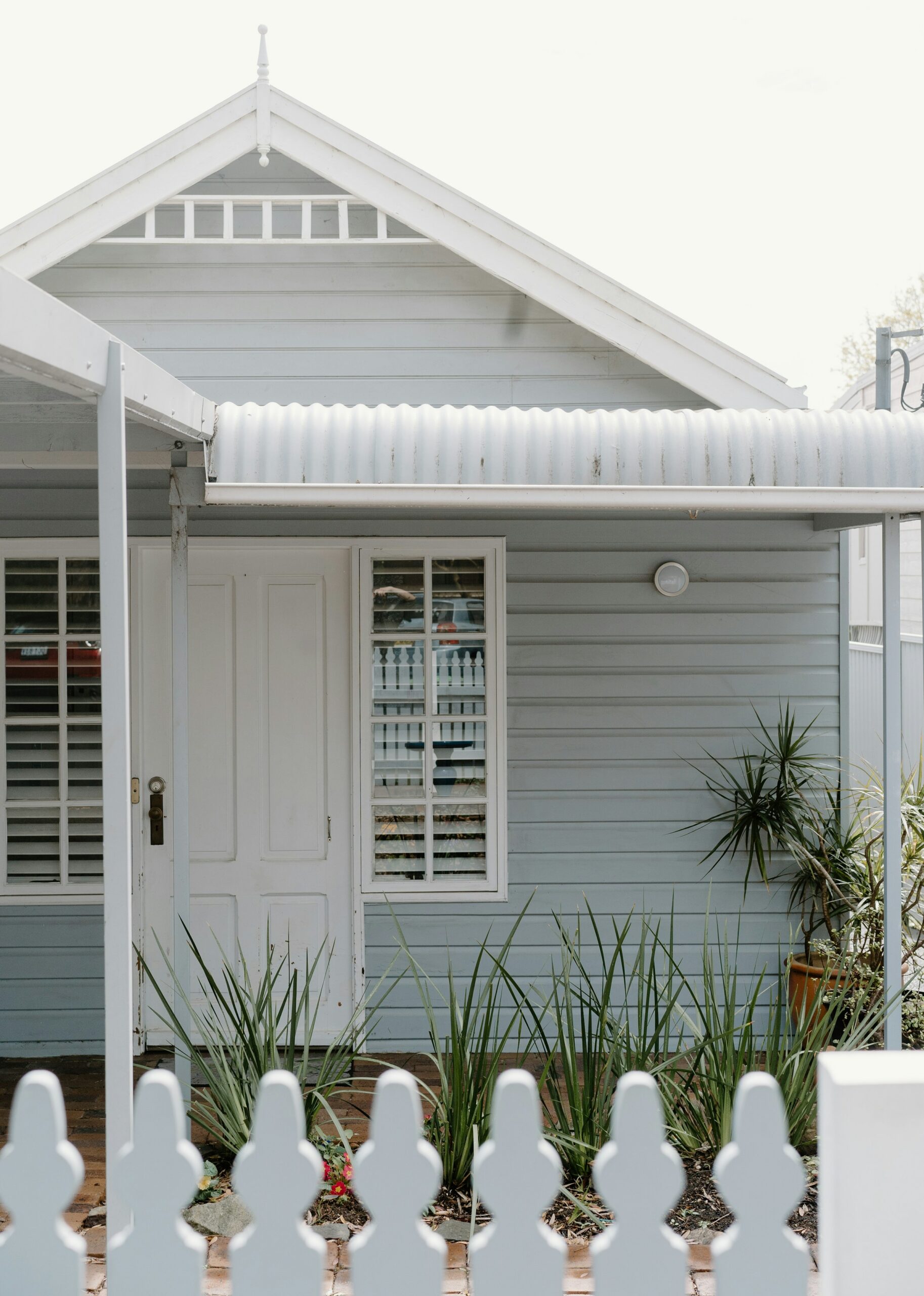 A white weatherboard house behind a picket fence